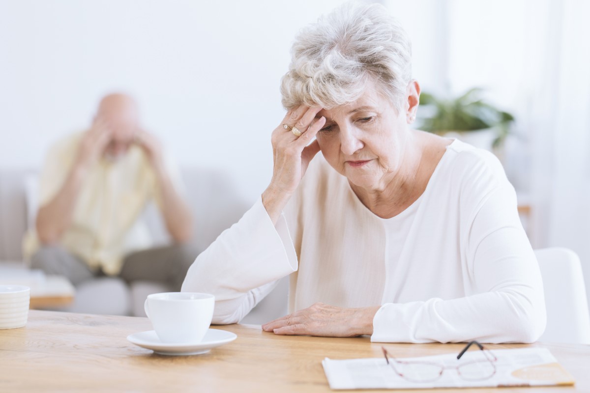 Eakas naine, kes hoiab oma pead, aju neuroloogiliste funktsioonide halvenemise tõttu, võimalik Alzheimeri tõbi. Eakas naine esiplaanil, pea kummardunud, toetub käele.