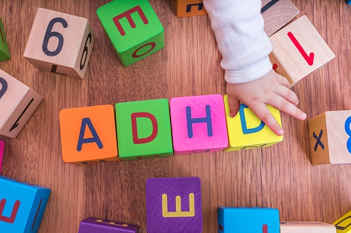 laste tähekuubikud, mis on paigutatud nii, et need moodustavad nime ADHD, lapse käega