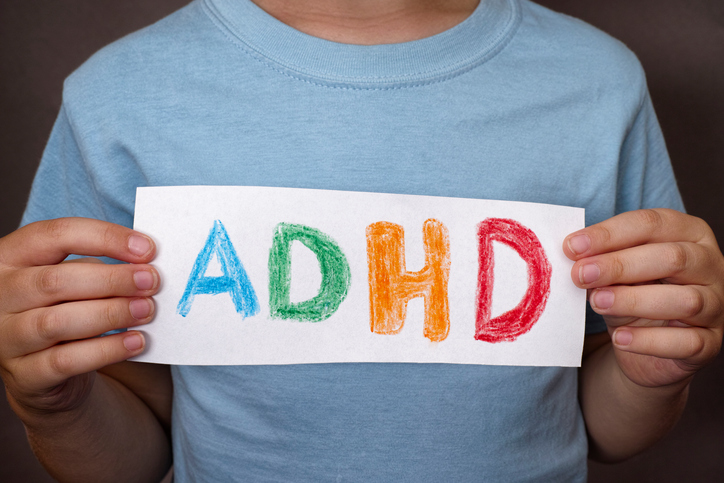 Poiss hoiab käes märki, millel on värviline ADHD märk